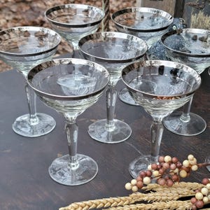 Two platinum bands encircle the rims of these clear glasses. Tall sherbet or champagne set of 8.  Displayed on dark wood table --Stalks of wheat laying nearby