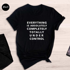 May include: Black t-shirt with the text "Everything is absolutely completely totally under control" printed in white.