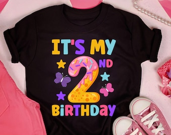 May include: Black t-shirt with the text "It's My 2nd Birthday" in colorful letters. The number 2 is a donut with pink frosting and sprinkles. There are colorful stars and butterflies around the text.