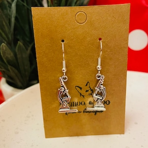 May include: A pair of silver microscope earrings on a brown card with the text "Daboo, born in beauty".