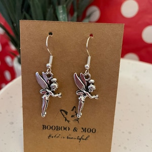 Puede incluir: Pendientes de plata con diseño de hada. Los pendientes están en una tarjeta marrón con el texto "Booboo & Moo" y "La vida es bella".