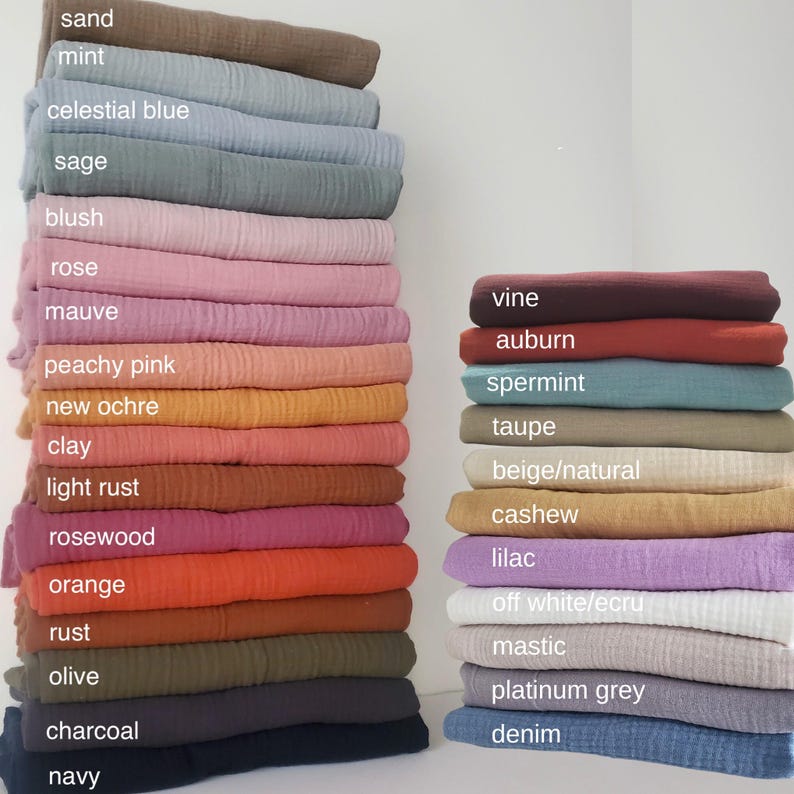 May include: Two stacks of folded muslin fabric in various colors. The left stack includes sand, mint, celestial blue, sage, blush, rose, mauve, peachy pink, new ochre, clay, light rust, rosewood, orange, rust, olive, charcoal, and navy.