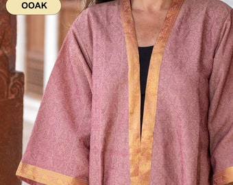Pode incluir: Um quimono rosa com detalhes dourados e um padrão floral. O quimono está aberto na frente e tem um decote em V.