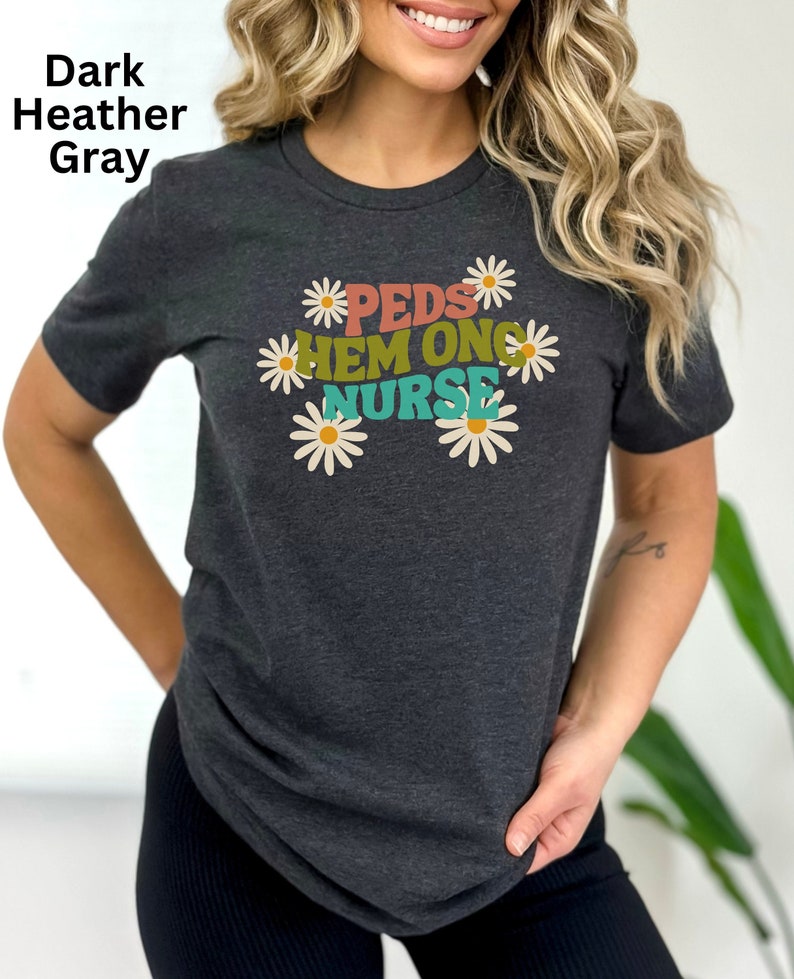 May include: Dark heather gray t-shirt with a daisy design and the text "PEDS HEM ONC NURSE" in colorful letters.