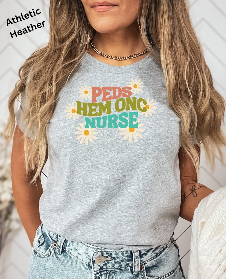 May include: Gray athletic heather t-shirt with a graphic design of daisies and the text "PEDS HEM ONC NURSE" in colorful letters.