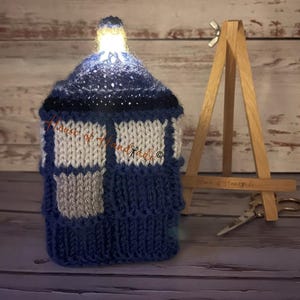 Patrón de tejido para funda de caja de bombones naranjas con forma de cabina de policía iluminada