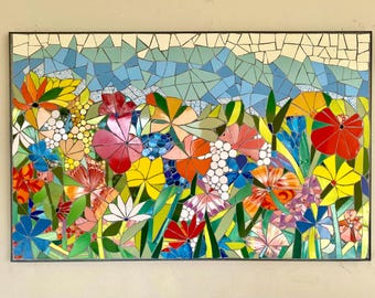 May include: A colorful mosaic wall art featuring a variety of flowers in shades of red, yellow, blue, green, and white. The flowers are arranged in a random pattern, creating a vibrant and eye-catching design.