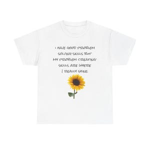 May include: White t-shirt with the text "I HAVE GOOD PROBLEM SOLVING SKILLS BUT MY PROBLEM CREATING SKILLS ARE WHERE I REALLY SHINE." A yellow sunflower is printed below the text. The t-shirt is a casual wear item.