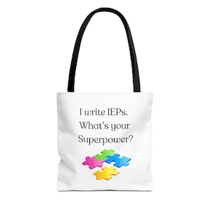 Könnte beinhalten: Weiße Tragetasche mit schwarzen Griffen. Auf der Tasche steht der Text "I write IEPs. What's your superpower?" und ein farbenfrohes Puzzleteil-Design. Zum Tragen von Gegenständen.