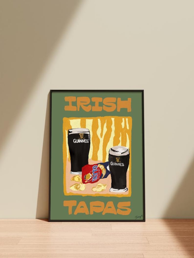 May include: A framed art print depicting two pints of Guinness and a packet of Tayto crisps. The words "IRISH TAPAS" are printed in orange block letters on a green background. The art has a minimalist style.