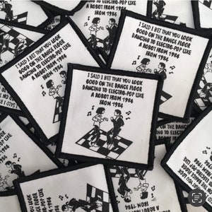May include: Square white patches with black embroidered borders. Each patch features the text "I SAID I BET THAT YOU LOOK GOOD ON THE DANCE FLOOR DANCING TO ELECTRO-POP LIKE A ROBOT FROM 1984" and a black and white illustration of two people dancing.