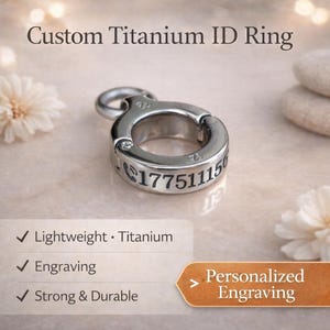 Könnte beinhalten: Ein individueller ID-Ring aus Titan mit eingravierter Telefonnummer. Der Ring ist silberfarben und hat ein kreisförmiges Design mit einer Scharnieröffnung. Der Text "Custom Titanium ID Ring" befindet sich oben im Bild.