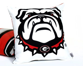 May include: Two decorative throw pillows. One pillow is white with a black and red bulldog graphic. The bulldog has a red collar with a white 'G' on it. The other pillow is black, red, and gray striped.