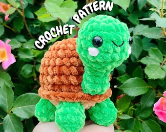 May include: Crochet pattern for a green and brown turtle amigurumi toy. The turtle has a smiling face with black eyes and white cheeks. The text "CROCHET PATTERN" is written in white letters on a black background.