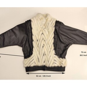 May include: Black leather jacket with a white fur panel on the back. The jacket has pockets and a zipper closure. The jacket measures 28.3 inches in length and 20.5 inches in width.