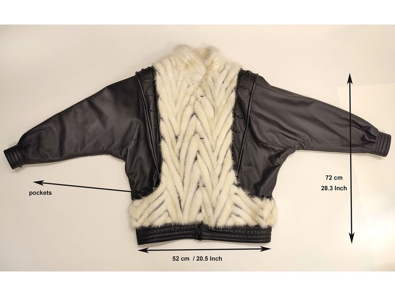 May include: Black leather jacket with a white fur panel on the back. The jacket has pockets and a zipper closure. The jacket measures 28.3 inches in length and 20.5 inches in width.