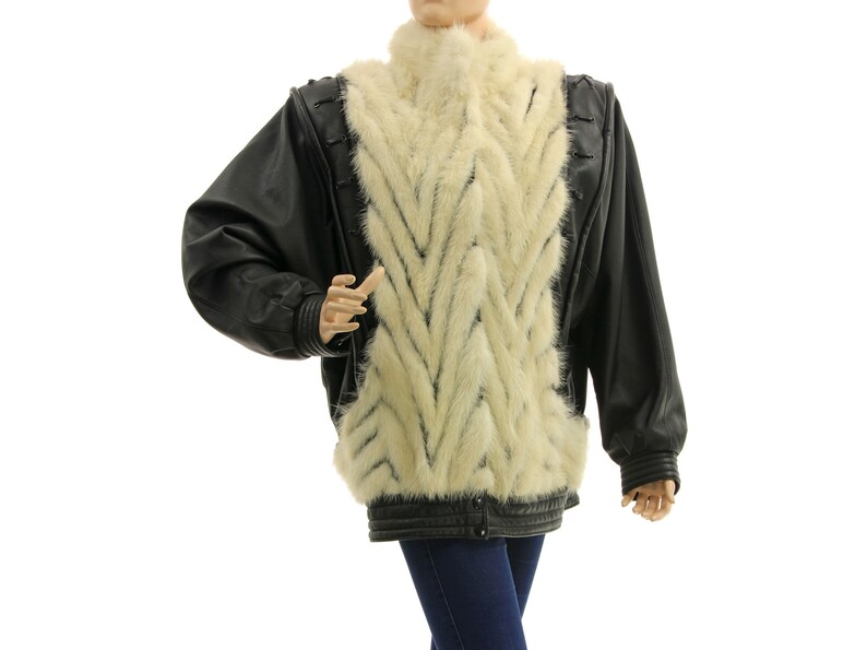 May include: A black leather jacket with a white fur panel down the front. The fur is arranged in a chevron pattern.
