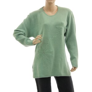 Könnte beinhalten: Ein langärmliger, hellgrüner Pullover mit einem Blumendesign. Der Pullover hat einen runden Ausschnitt und ist aus einem weichen, bequemen Material gefertigt.