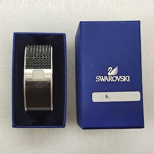 Peut inclure: Un bracelet noir et argent avec un motif en cristal dans une boîte bleue avec le logo Swarovski et le numéro 6.