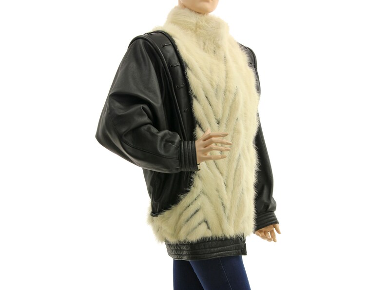 May include: A black leather jacket with a white fur collar and lining. The fur is arranged in a chevron pattern.