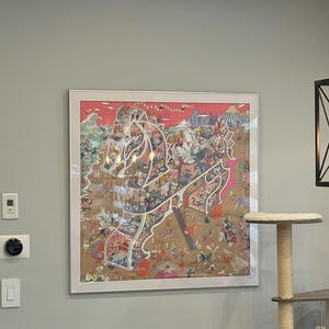 May include: A framed artwork featuring a detailed illustration of a carousel horse filled with figures and scenes. The artwork has a white frame and is mounted on a gray wall. The color palette includes pink, tan, and various other colors.