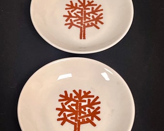May include: Two white ceramic dishes with a brown stylised tree design in the centre.