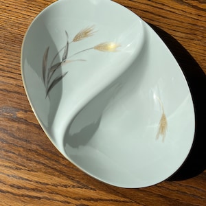 May include: A white ceramic serving dish with a divided design. The dish features a gold rim and a delicate wheat design in gold and gray.