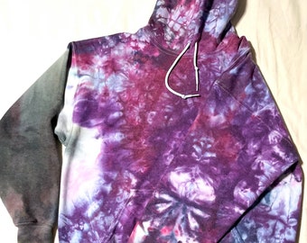 May include: Purple, blue, and gray tie-dye hoodie with a white drawstring. The hoodie has a large pocket on the front.