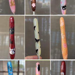 K&ouml;nnte beinhalten: Eine Sammlung von Glitzerstiften mit verschiedenen Designs. Die Stifte zeigen Bilder von Katzen, Schmetterlingen, Zeichentrickfiguren und anderen dekorativen Elementen. Die Stifte sind in verschiedenen Farben erh&auml;ltlich, darunter Rosa, Blau, Orange und Rot.