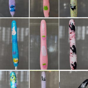 K&ouml;nnte beinhalten: Eine Sammlung glitzernder, dekorativer Stiftaufs&auml;tze mit verschiedenen Designs. Die Aufs&auml;tze zeigen Zeichentrickfiguren, Erdbeeren, Stinktiere und andere Grafiken. Einige Aufs&auml;tze haben Text, darunter "I hate people."