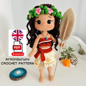 May include: Crochet pattern for a Moana doll with a flower crown, brown hair, a red and white top, a tan skirt, and a brown surfboard.