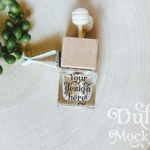 Könnte beinhalten: Ein hölzerner Auto-Lufterfrischer mit einer durchsichtigen Glasflasche und einem weißen Holzanhänger. Die Flasche trägt den Text "Your design here".