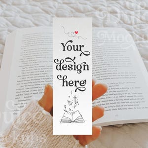 May include: A white bookmark with black and red illustrations. The bookmark has the text "Your design here" in black cursive font. The bookmark is being held by a hand in a white sweater.