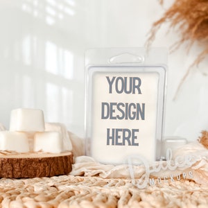 Könnte beinhalten: Ein durchsichtiger Plastikbehälter mit einem weißen Etikett, auf dem "YOUR DESIGN HERE" steht. Der Behälter steht auf einer geflochtenen Weidefläche mit ein paar weißen Wachswürfeln im Hintergrund.