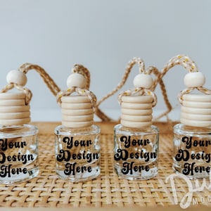 May include: Four clear glass bottles with wooden stoppers and string hangers. Each bottle has a black label that says "Your Design Here". The bottles are sitting on a woven brown basket.