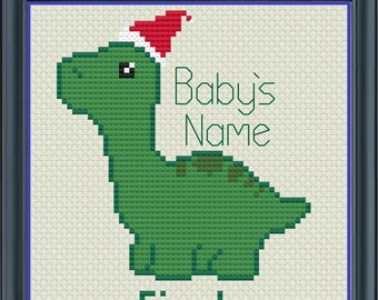 May include: A green dinosaur wearing a red Santa hat with the text "Baby's Name" and "First Christmas 2022" underneath.
