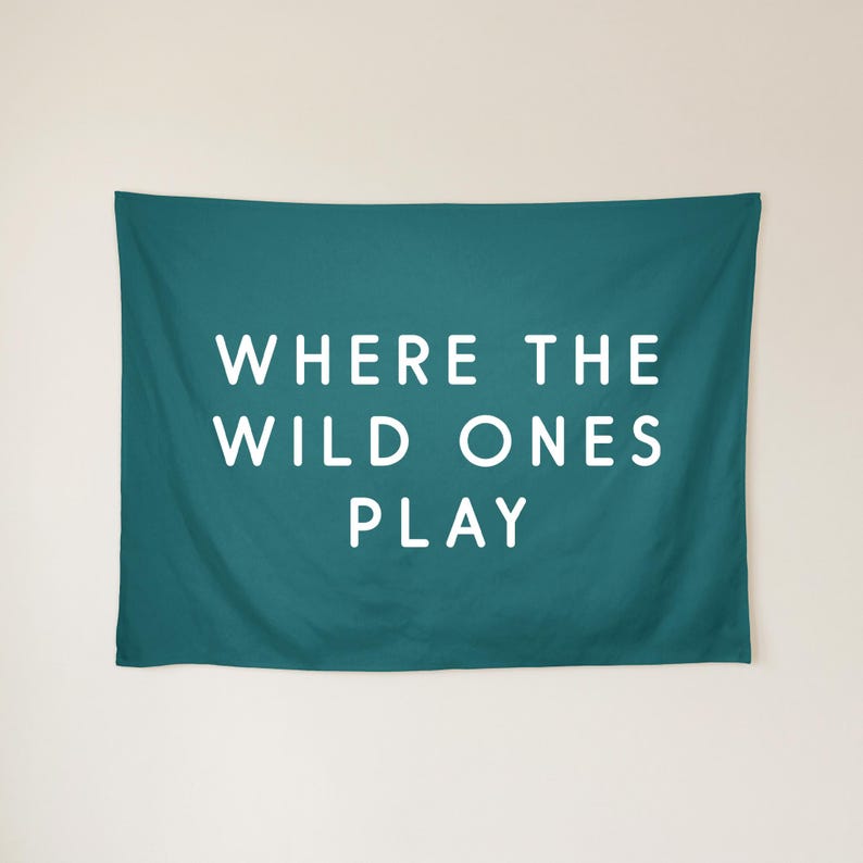 May include: A rectangular teal wall tapestry featuring the white text WHERE THE WILD ONES PLAY centred in a clean sans-serif font. The fabric has a smooth, matte finish and hangs flat against the wall, displaying clear, bold lettering.
