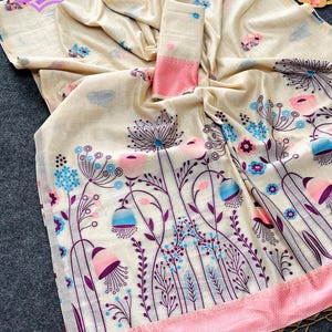 Floral linen saree pastel color Indian saree
Designer saree with printed pallu tassels
Soft cotton linen saree elegant floral design
Traditional Indian saree modern pastel style
Lightweight festive saree with blouse piece