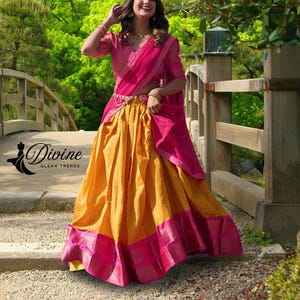 May include: A vibrant, traditional Indian outfit featuring a bright yellow skirt with a pink border and a matching pink top and shawl. The outfit is embellished with gold accents. The image includes the text "Divine Gleam Trends".