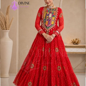 May include: A floor-length red dress featuring long sleeves, a tiered skirt, and a vibrant, multi-colored embroidered panel on the chest. The fabric is adorned with a repeating circular pattern in green and gold, with silver trim on the cuffs.