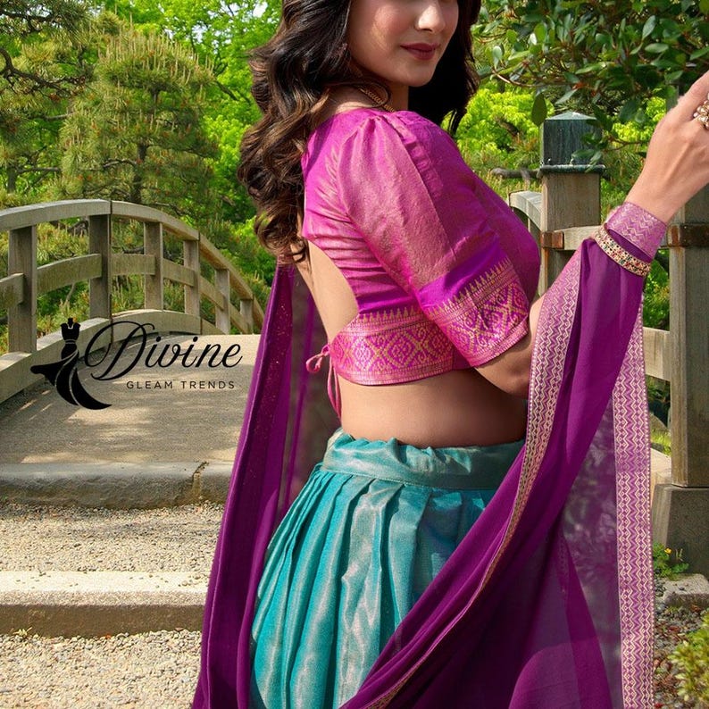 May include: A vibrant ensemble featuring a magenta blouse with intricate gold detailing on the sleeves and hem. The outfit includes a turquoise skirt and a flowing purple shawl. The image displays the text "Divine Gleam Trends".