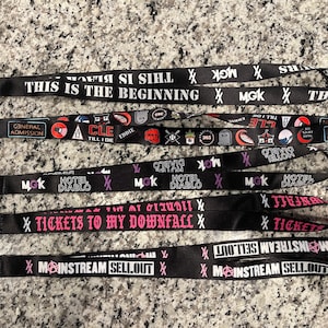 Puede incluir: Un conjunto de seis cordones negros con varios dise&ntilde;os y textos. Los cordones presentan los textos "This is the beginning", "General Admission", "Hotel Diablo", "Tickets to My Downfall" y "Mainstream Sellout".