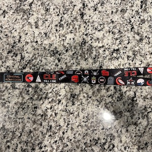 Puede incluir: Lanyard negro con texto rojo y blanco que dice "General Admission" y "CLE TILL I DIE". El lanyard tambi&eacute;n presenta varios gr&aacute;ficos, incluyendo una calavera, un bate de b&eacute;isbol y una ola.