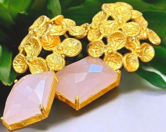 May include: Gold earrings with a delicate floral design and a large, pale pink gemstone.