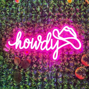 May include: Neon sign with the word "Howdy" in white letters on a pink background. The sign is shaped like a cowboy hat.
