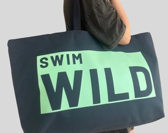 May include: A navy blue tote bag with a green rectangle and the text "SWIM WILD" in black.