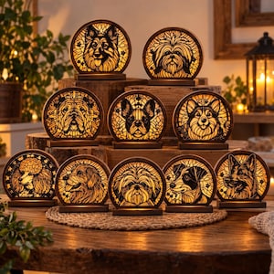 May include: A collection of ten circular, illuminated wooden dog portraits featuring intricate laser-cut silhouettes of various breeds, including a poodle, bulldog, and corgi, each glowing with a warm internal light and mounted on a flat base.