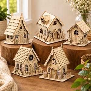 Könnte beinhalten: Eine Sammlung von fünf Miniaturhäusern aus Holz mit komplexen lasergeschnittenen Details, darunter Bogenfenster, Schindeldächer und dekorative florale Elemente. Jedes Bauwerk ist aus hellem Holz gefertigt und steht auf einer flachen Basis.