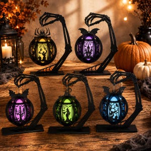 May include: Five black skeleton hand stands holding spherical lanterns with Halloween-themed cutouts. Each lantern glows in a different color, including yellow, purple, pink, green, and blue, featuring silhouettes of spiders, bats, and witches.