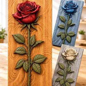 K&ouml;nnte beinhalten: Drei rechteckige Wandtafeln mit Reliefschnitzereien einzelner Rosen. Eine Tafel ist aus Naturholz mit einer roten Rose, eine aus blau gebeiztem Holz mit einer blauen Rose und eine aus grau gebeiztem Holz mit einer cremefarbenen Rose.